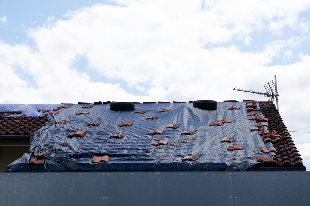 black tarp on roof after strong typhoon wind damage hail thunderstorm